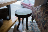 Vintage African wooden stool with rounded top, aged dark wood, and curved legs.