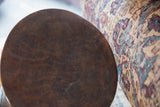 Circular dark brown wooden top of vintage African stool, exhibiting aged texture.