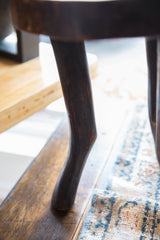 Handmade dark wooden leg of vintage African stool, showing grain and age.