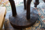Hand-carved dark brown base of a vintage African wooden stool, showing natural imperfections.