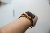 A thin vintage bronze cuff bracelet styled on a wrist with a watch.