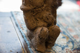 Close-up of the African terracotta Nkisi fetish figure's rough, earthy brown surface.
