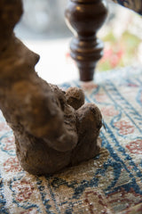 Earthy, textured base of the antique African terracotta figure on a hand-knotted patterned rug.