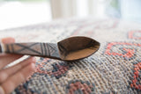 Detailed linear carvings on the aged, dark wood bowl of a Tuareg spoon.