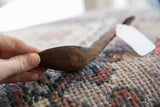 Side profile of the hand-carved wooden spoon, showing the deep bowl and aged texture.