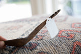 The aged patina and dark, hand-carved texture of a vintage wooden spoon.