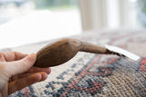 The unique profile and aged, hand-carved texture of the vintage wooden spoon.