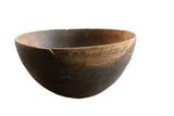 Vintage African wooden bowl with a dark, textured body and a lighter carved rim.