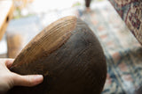 Hand-stitched repairs and carved textures on the exterior of a vintage African wooden bowl.