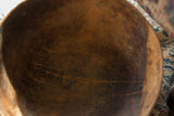 Historic metal staple repair along a crack inside the dark, textured wooden bowl.