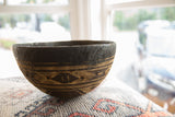 Vintage African wooden bowl detail, featuring carved geometric patterns on dark, aged wood.