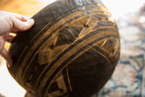 Intricate carved patterns and aged texture on a dark vintage African wooden bowl.