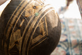 Detail of vintage African wooden bowl showing etched patterns, dark repairs, and green patina.