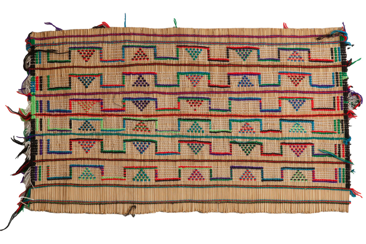 Vintage African Tuareg mat woven from straw with colorful geometric patterns.