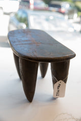 Dark hand-carved leg of a vintage Senufo wood stool with SKU tag.