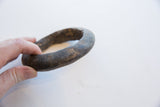 A hand holds the antique Neolithic marble bracelet, showing its substantial form.
