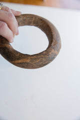 Profile view of a hand-carved Neolithic marble bracelet showing its mottled brown patina.