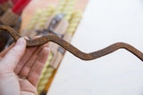 The textured, rusted surface of the hand-worked vintage African iron snake.
