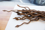 Multiple vintage African iron snakes intertwined, displaying weathered rust and pointed heads.