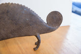 The ridged back and coiled, spiral-carved tail of a handmade African chameleon figure.