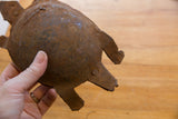 A hand holds the vintage African iron turtle, showing its handmade form and rusted patina.