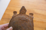 Close-up of the rustic, etched facial details on the vintage African iron turtle's head.