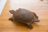 Angled profile of the handmade iron turtle's simple form and heavy, rusted patina.