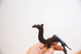 Hand holding the vintage African camel collectible, highlighting its dark patina and slender form.