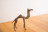 Side profile of a vintage African camel sculpture showing its slender form and aged patina.