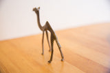 The textured tail and slender back legs of a vintage African camel figurine.