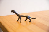 The slender, stylized body of a handmade African cheetah sculpture with a dark patina.