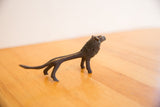 Side profile of the vintage African lion's slender body and dark, textured patina.