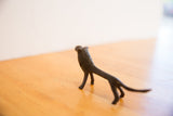 Rear view of the vintage lion sculpture showing its slender body and dark patina.