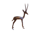 Vintage African left facing gazelle sculpture with a dark, smooth patina and tall horns.