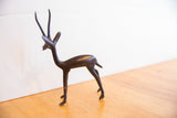 Slender form and dark handmade patina of the vintage left-facing gazelle sculpture.