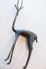 Dark patina on the curved back and long neck of a handmade vintage gazelle figure.