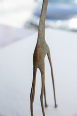 Aged, oxidized metal with a greenish patina on the vintage giraffe figurine.
