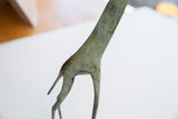 Close-up of vintage African giraffe sculpture with bright oxidized green patina and textured surface.