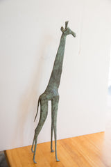 Vintage African giraffe statuette in profile, showing its slender form and textured green patina.