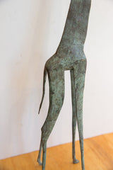 View of the vintage giraffe sculpture's rear legs and tail with a green oxidized patina.