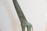 Close view of the brightly oxidized green finish on the vintage giraffe's slender neck.