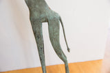 Stylized hind legs and tail of a brightly oxidized vintage giraffe figure.
