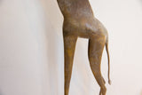 The aged, textured patina on the body and slender legs of a vintage African giraffe figure.