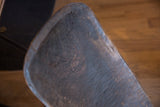Angled detail of vintage African wooden slot chair's dark, worn seat with rich patina.