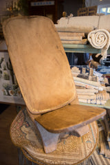 Vintage African wooden slot chair seen from an angle, highlighting its smooth, aged wood surface.