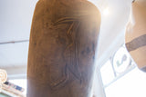 Hand-carved bird with a crosshatch pattern on the dark wood back of the chair.