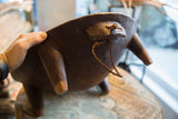 Vintage hand carved African bowl underside, showing dark wood texture, rope, and a leg.