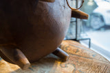 Textured dark wood of vintage African hand-carved bowl with leg on patterned rug.