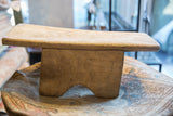 Vintage hand-carved African stool displaying textured wood and a distinct arched base.