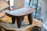 Hand-carved Senufo wood stool showing its aged patina and sculptural form.